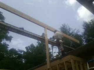 Carpenter setting a ridge beam over a new addition frame — Ice Dam Removal by Roofing Brothers in Gaylord