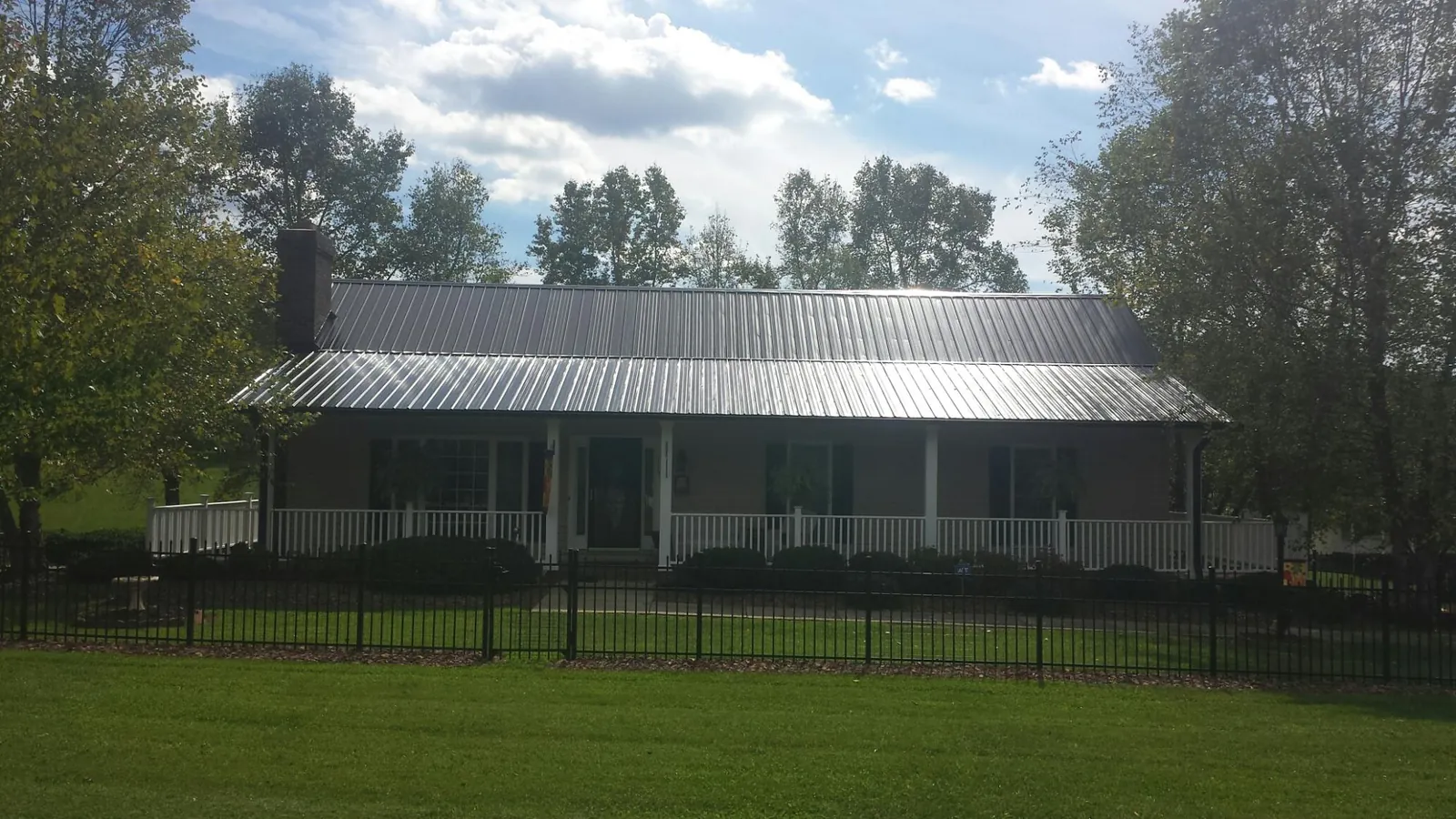 Gray metal roof on a brick ranch with a full width front porch — Gutter Guard Installation work by our crew in Gaylord