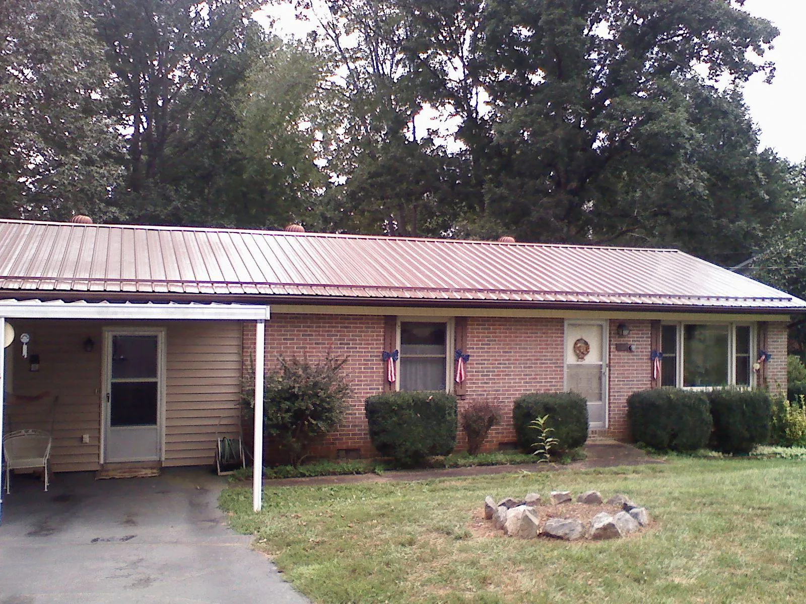 Bronze metal roof and carport on a brick ranch home — Roof Repair work by our crew in Gaylord